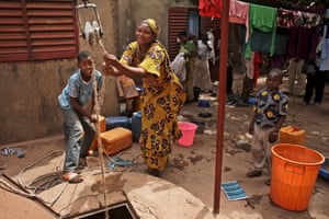 Sally Cisse, right and and neighbour Mamadou Coulibaly, pull up unclean water from a deep well in the courtyard of a compound in Kalabancoro, a town on the outskirts of Bamako. Population growth and increasing urbanisation in many parts of Africa are creating more challenges. Many countries do not have the systems for dealing with growing towns. Instead they are often using approaches adapted from rural areas<br>