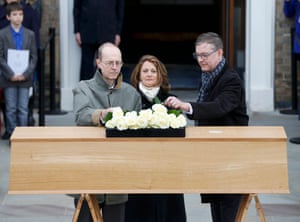 Canadian-born carpenter Michael Ibsen, left, the King’s 17th great-grandnephew, places a rose on the oak coffin.