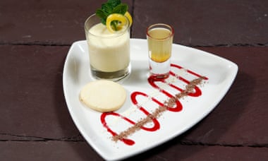 The lemon posset on a triangular white plate with a decorative red swirl