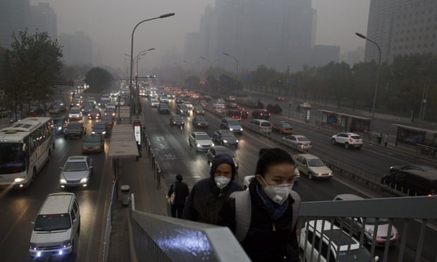 Pedestrians wear masks against the pollution as they cross an overhead bridge over a busy highway in Beijing, China, on  November 29, 2014.