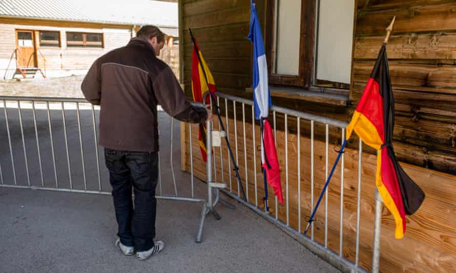 A man sets up a memorial with the flags of Germany, Spain and France in Vernet.