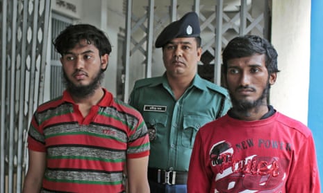 A policeman escorts two of the men charged with killing the blogger Washiqur Rahman to a media briefing