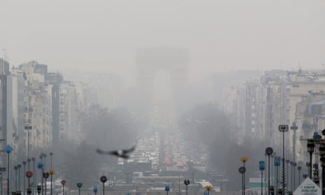 A faint view of the landmark Arc de Triomphe is seen through a foggy haze in Paris.
