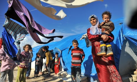 A Syrian woman carries her child outside their makeshift house at the refugee camp of Qah along the Turkish border in the village of Atme in the northwestern province of Idlib, on March 17, 2013.