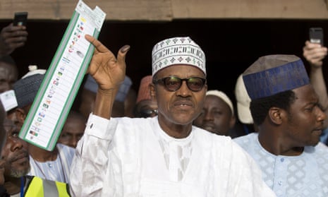 Muhammadu Buhari holds his ballot paper in the air before casting his vote in his home town of Daura, northern Nigeria, on Saturday.