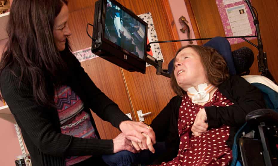 A woman suffering from locked-In syndrome after a brain tumour, cared for at home by her family