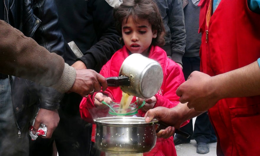 A girl receives soup from Kafaf, a charitable foundation, in Yarmouk