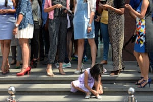A young girl puts on her shoes next to women wearing stilletos waiting to take part in the Stilleto Run in Bangalore, India