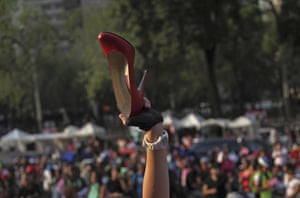 A woman holds up her high-heeled shoe after reaching the end of a bike ride, in Mexico City