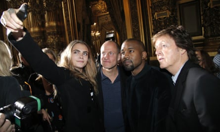 Cara Delevingne, takes a photographer with Woody Harrelson, Kanye West and Paul McCartney prior to the Stella McCartney show.