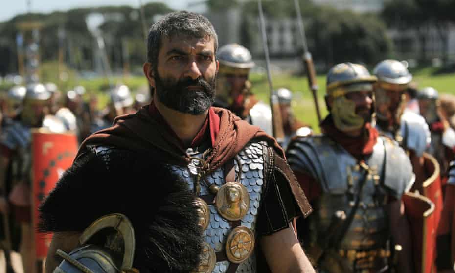 Men dressed as ancient Roman soldiers march through Circus Maximus.