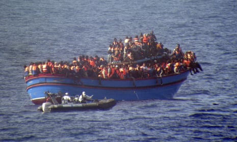 A motor boat from the Italian frigate Grecale approaches a boat overcrowded with migrants in the Mediterranean