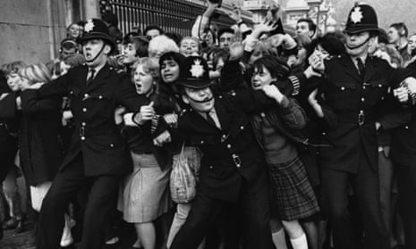 Policemen struggle to restrain young Beatles fans outside Buckingham Palace as the band receive their MBEs , October 1965.