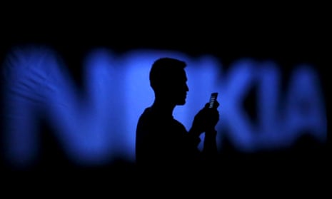 man holding a smartphone silhouetted on a Nokia logo