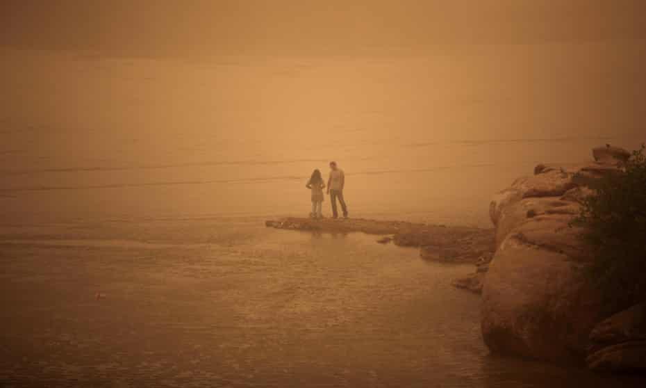 An Iranian couple stands on the shore of the Arvandrud river as a heavy sand storm hits the city of Ahvaz in the southwestern province of Khuzestan.