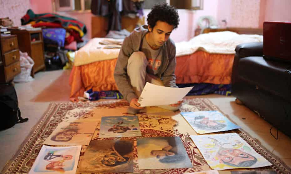 Art student Hussein Adel sitting on the floor his art work spread out