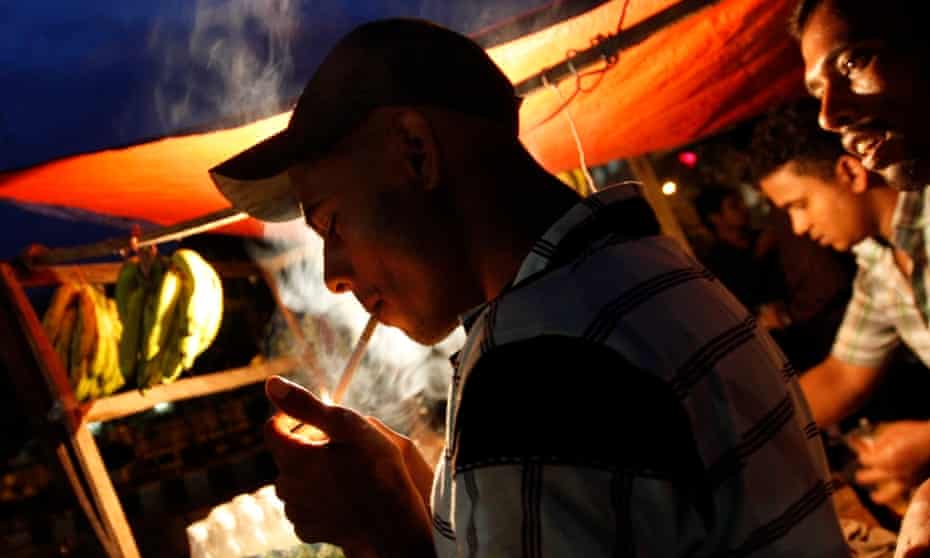 A man lights a cigarette in front of a roadside tea stall in Dhaka, Bangladesh.