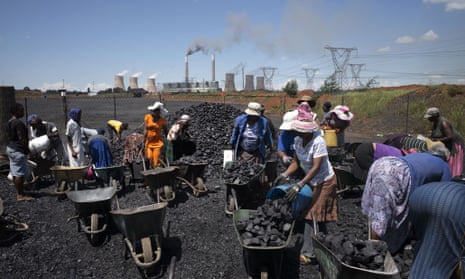 A file photo taken on February 5, 2015 shows women from the coal dust covered and power line pollution exposed Masakhane settlement filling their wheel barrows for a load of free coal provided by a nearby mine in Emalahleni. The Masakhane settlement, mainly consisting of migrant workers who converged to the coal rich Witbank region to search for job opportunities, has no access to the electricity grid, despite being only two kilometres away from the Duvha power station belonging to the embattled South African sole energy provider Eskom, and despite being criss-crossed by high tension power lines.