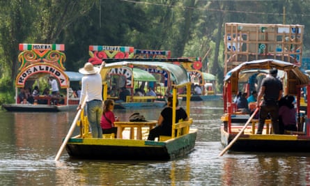 Tourists ride on a bright flat-bottomed boat on Lake Xochimilco