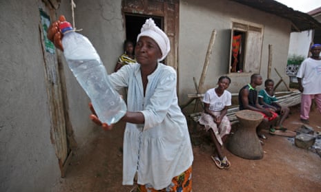 A Liberian woman washes her hands from a bottle of chlorine water to curb the spread of Ebola in Jene Wonde village, November 2014.