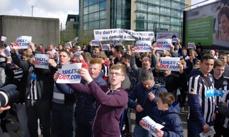 Newcastle United fans shout and hold banners outside St James' Park.