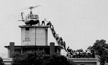 Evacuees are helped aboard an Air America helicopter perched on top of a building in Saigon.