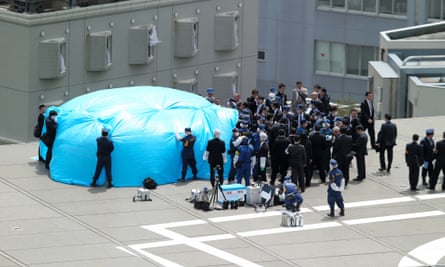 Investigators check a drone, under tarpaulin, on the roof of the prime minister's office. The camera-equipped drone produced a low level of radiation, police said.