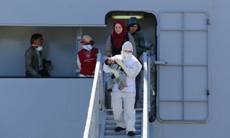 An officer feeds a baby as rescued migrants disembark from an Italian navy vessel in Augusta, Sicily.