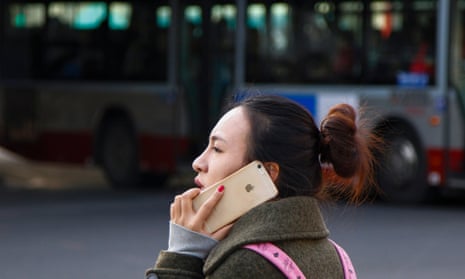 A woman uses her iPhone while waiting to cross an intersection in Beijing, China, 28 January 2015.