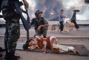 1968  A South Vietnamese soldier crouches next to badly bleeding woman while awaiting medical aid during an attack by the Viet Cong