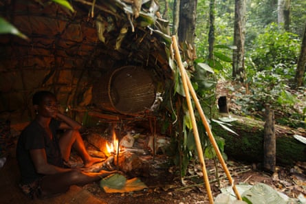 Baka man taking shelter in a Mongolu at a forest hunting camp, Cameroon