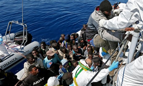 Migrants are helped aboard an Italian rescue boat