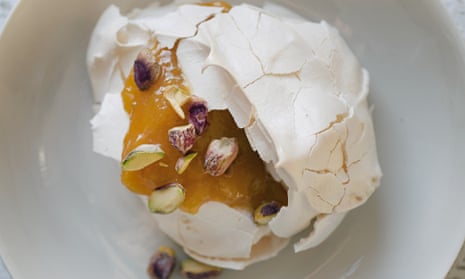 Meringue in a bowl cracked open, with syrupy fruit in the middle