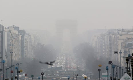 A faint view of the landmark Arc de Triomphe is seen through a foggy haze in Paris