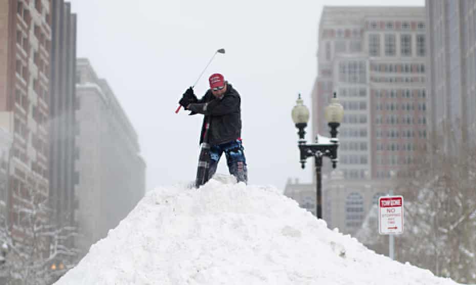 A Bostonian tees off from the top of a snow mound at in central Boston.