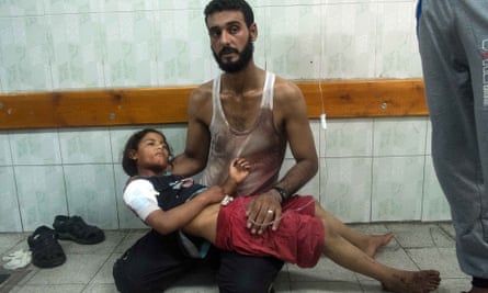 A father comforts his daughter injured during an Israeli strike on the UN school at Beit Hanoun during the 2014 Gaza war.