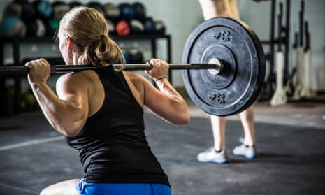 A woman does squats at a Crossfit gym.