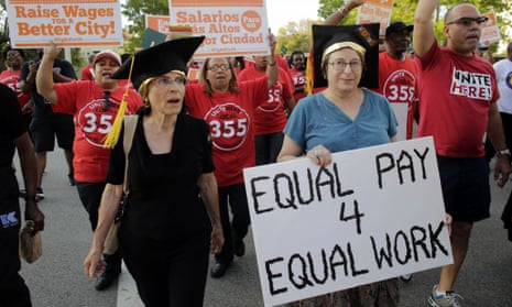 A woman carries a sign for equal pay as she marches with other Fight for 15 protesters in support of raising the minimum wage to $15 an hour.