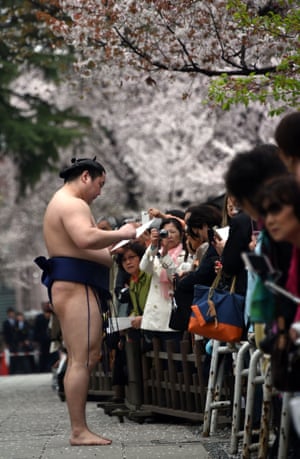 A sumo wrestler signs autographs for fans.