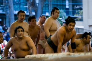 Sumo wrestlers watch fellow athletes compete.