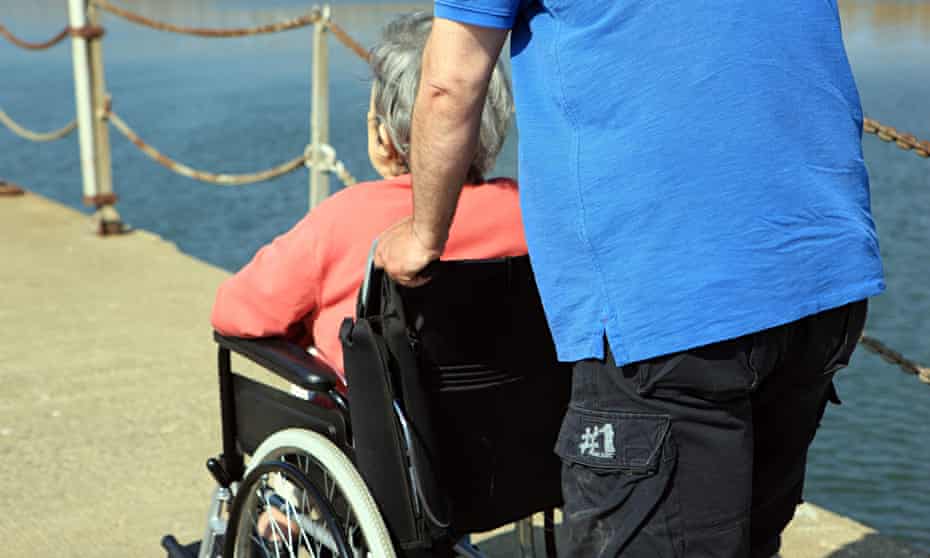 Man pushing an elderly lady in a wheelchair