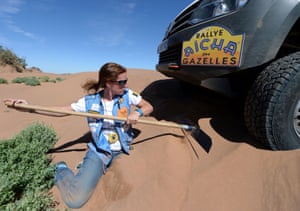 A member of the Portugal's Volkswagen team digs their vehicle out of the sand.