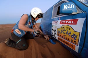 A member of France's Toyota team digs their vehicle out of the sand ...