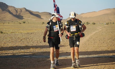 Sir Ranulph Fiennes (right) and his trainer Rory Coleman crossing the finish line of the first stage of his attempt to become the oldest Briton to complete the Marathon des Sables.