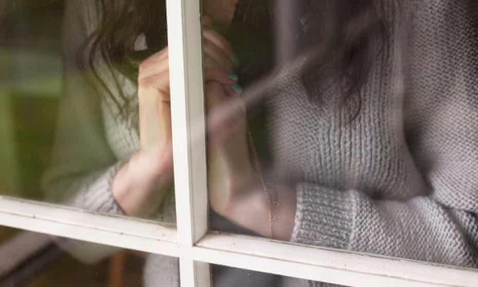 Woman with clasped hands looking out window