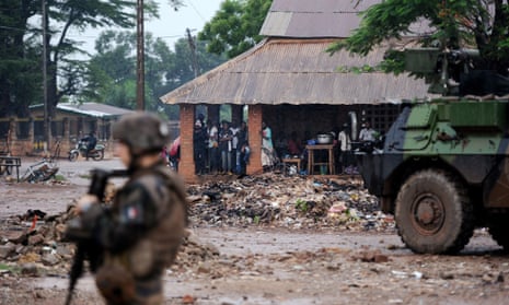 French soldiers of the Sangaris force patrol as locals take shelter from the rain on July 8, 2014 in the Fatima area of Bangui. 