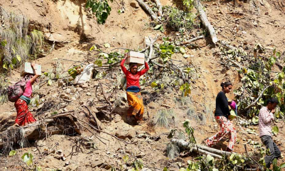 People cross a landslide zone after collecting relief material in Baluwa village, Gorkha district, close to the epicentre of the 25 April earthquake. Villagers were distributing emergency provisions among themselves on 30 April, as official aid and rescue operations continued to be held up.