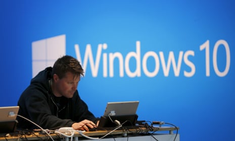 A man works on a laptop computer near a Windows 10 display at Microsoft Build in San Francisco.