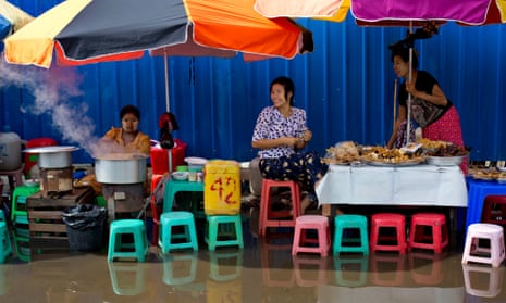 Vendors prepare food on a street corner flooded with a few inches of rain water in downtown Yangon, Myanmar.