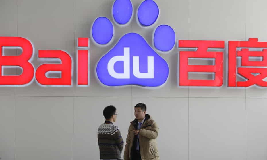 People talk in front of Baidu's company logo at its headquarters in Beijing, China.